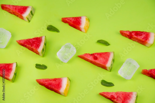 watermelon chunks with fresh mint leaves and ice cubes on a pastel green background