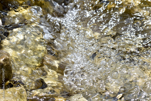 Running water in a stream with bubbles and stones