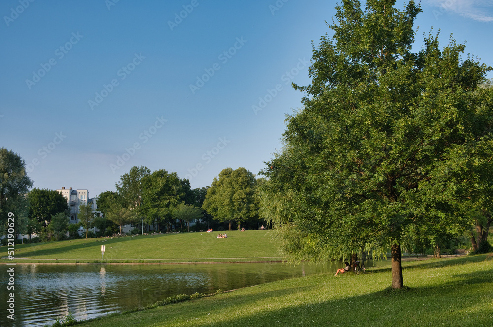 Mollsee im Westpark München im Sommer bei blauem Himmel mit Menschen