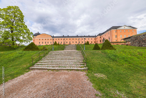 Beautiful exterior view of Royal Palace with green grass lawn on front and cloudy sky on background. Sweden. 