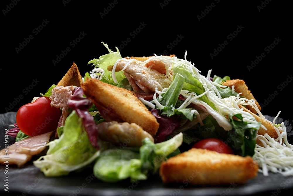Caesar salad on a black plate. Horizontal