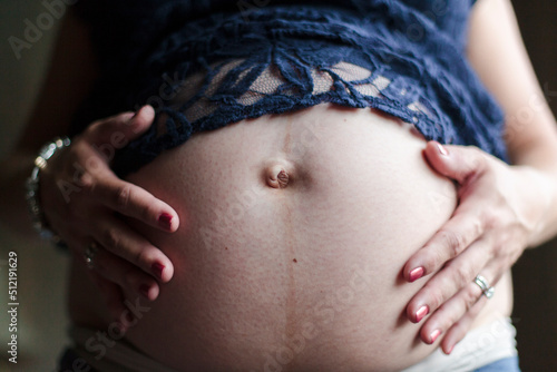 A woman holds her hands on her pregnant belly. photo