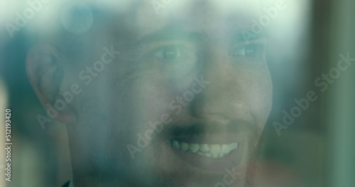 Confident man smiling looking out window thinking. Person reflection seen through glass
