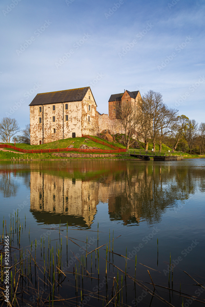 Medieval Kastelholm Castle and its reflections on a calm river in Åland Islands, Finland, on a sunny day in the summer.