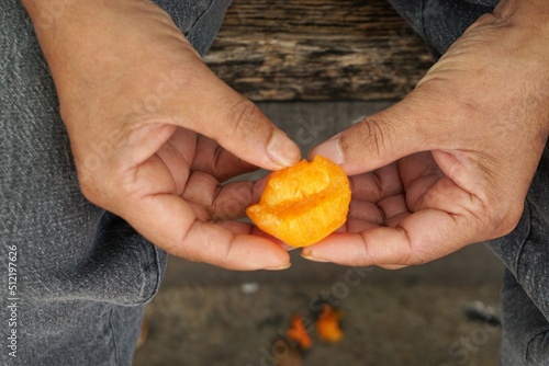 Orangene Obstfrucht in Händen von asiatischem Mann 