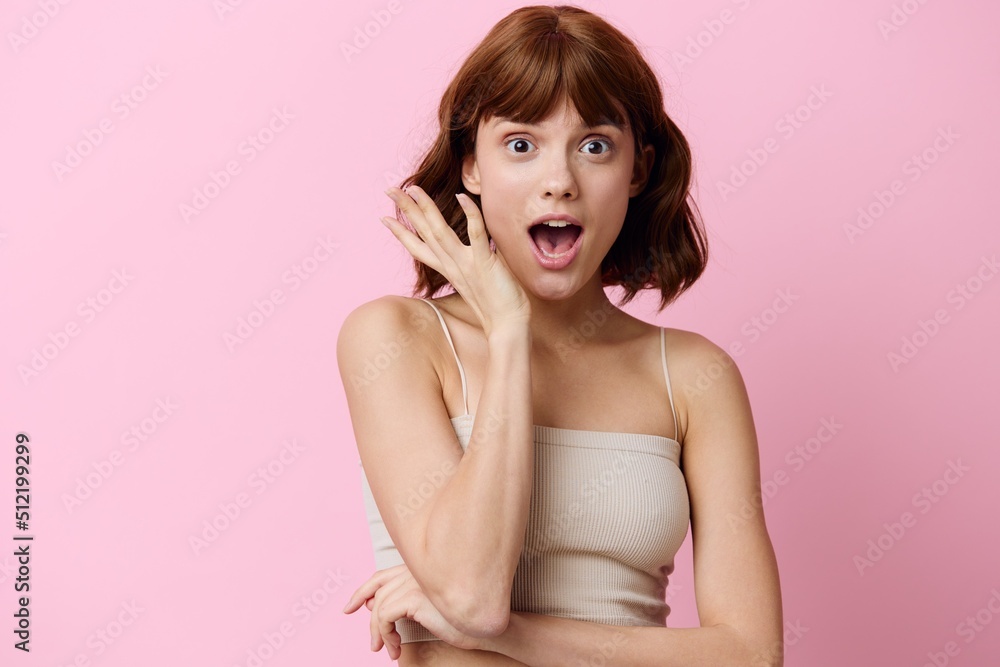 a happy, very emotional woman stands on a pink background with her mouth wide open in surprise and holds her hand near her face a happy, very emotional woman stands on a pink background with her mouth wide open in surprise and holds her hand near her face