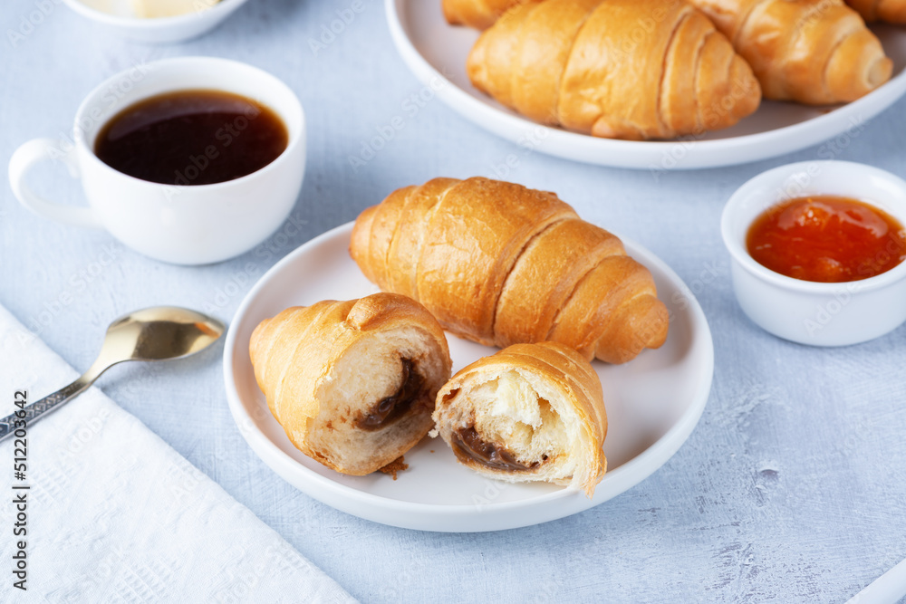 A freshly baked French Croissant, coffee, butter and jam