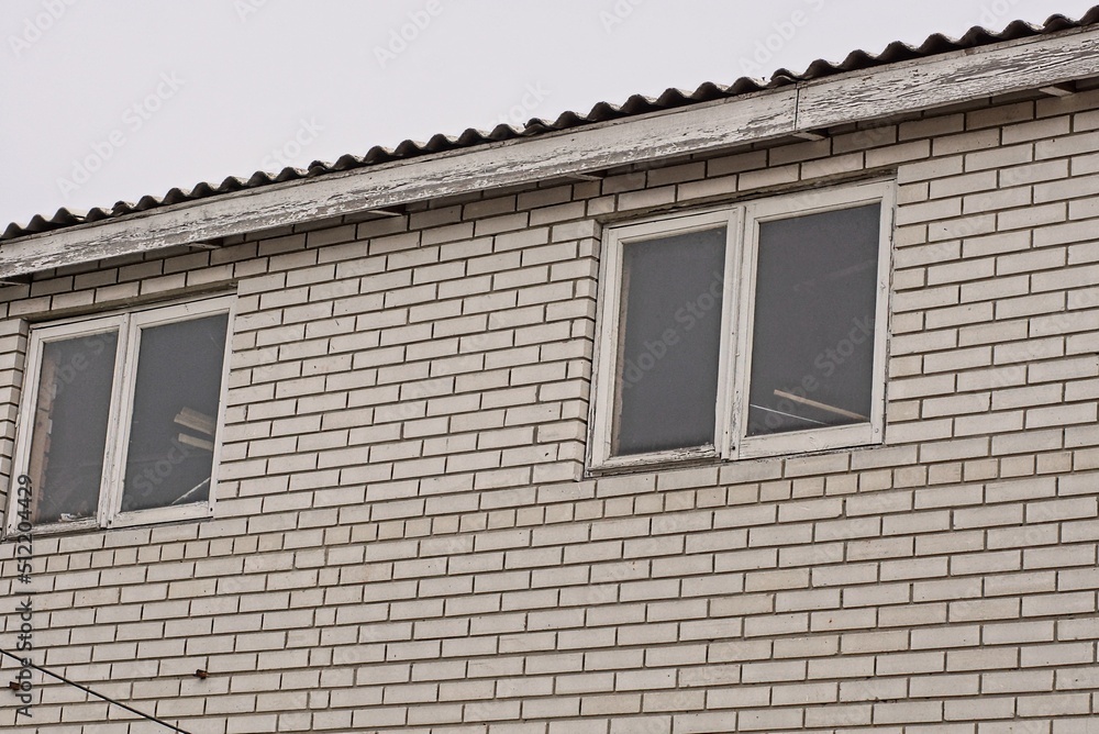 white brick attic of a private house with windows against a gray sky