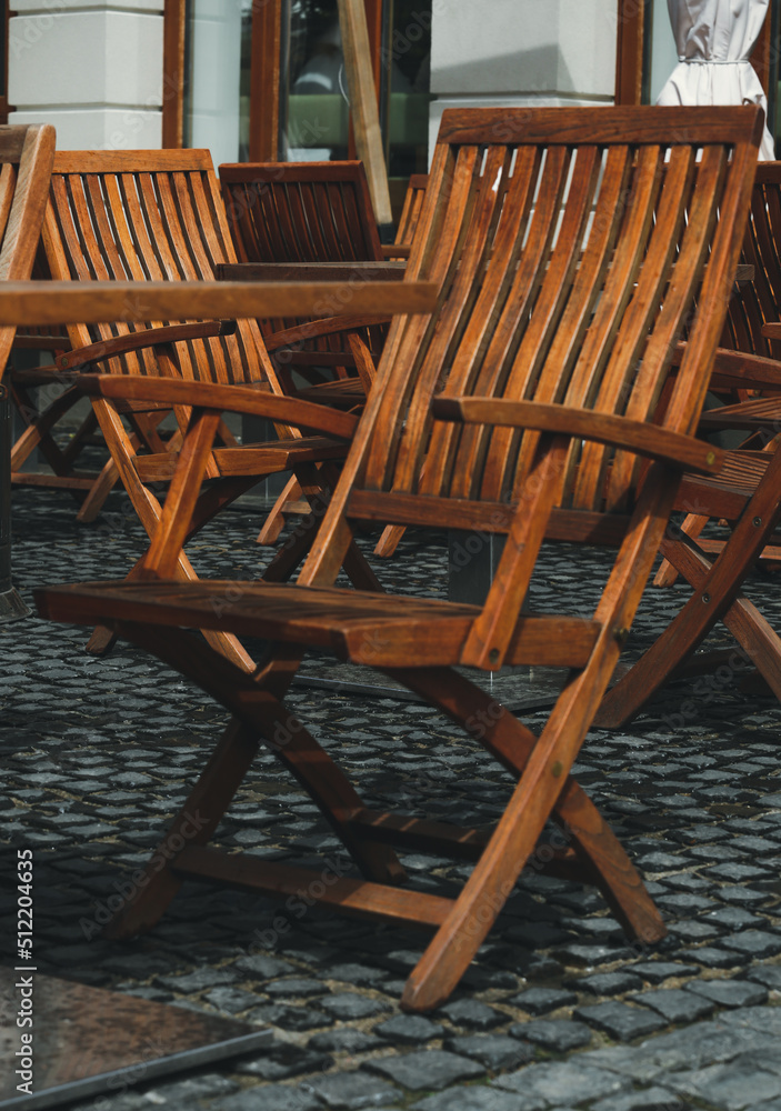 There are no people on the wooden terrace, on which there are wooden chairs, on the dark wooden floor. A deserted street cafe with wooden chairs. Street cafe, bistro, restaurant. There are no people on the wooden terrace, on which there are wooden chairs, on the dark wooden floor. A deserted street cafe with wooden chairs. Street cafe, bistro, restaurant.