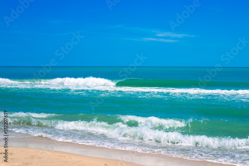 Blue sea with a wave and a sandy shore, on the horizon with a blue sky. Seascape in summer