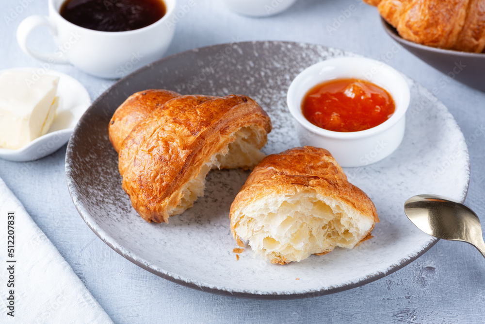 A freshly baked French Croissant, coffee, butter and jam