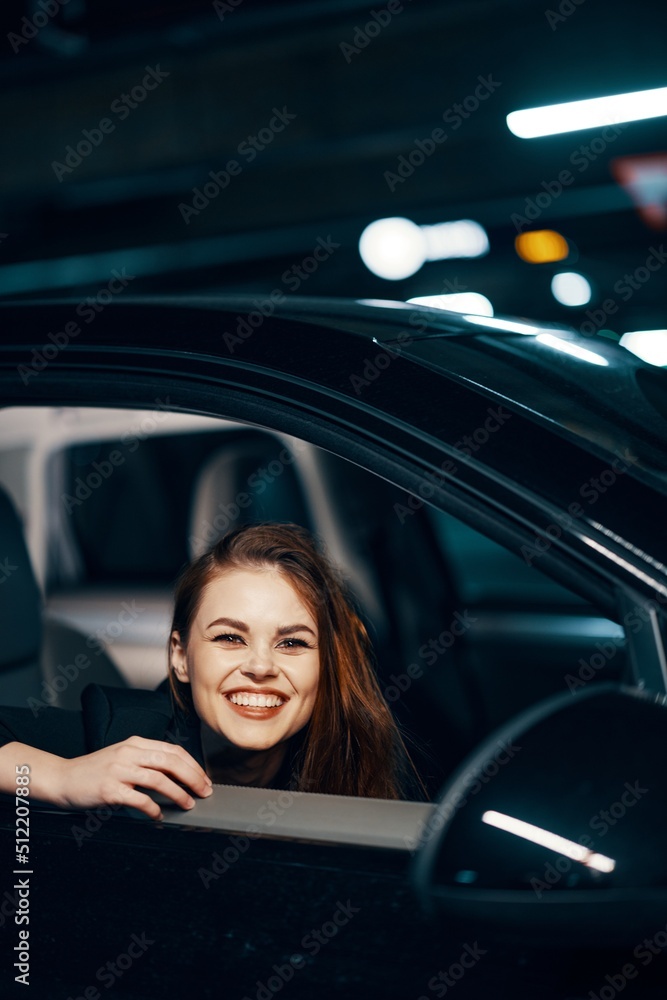vertical photo from the side, at night, of a woman sitting in a car and looking out of the window, laughing happily into the camera, closing her eyes