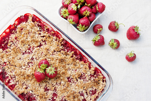 Homemade strawberry crumble is an English dessert. Baked berries covered with shortcrust pastry crumbs. Sweet and sour summer dessert. top view
