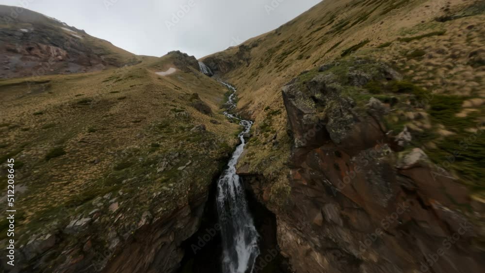 Fast FPV drone shot up along the mountain dew towards to the big waterfall Fast FPV drone shot up along the mountain dew towards to the big waterfall