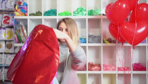 a woman inflates of helium from a foil balloon in the shape of a heart.