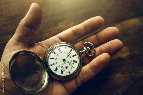 Vintage pocket watch is in your hand.A man's hand holds a vintage mechanical watch on a wooden background. The passing time. photo