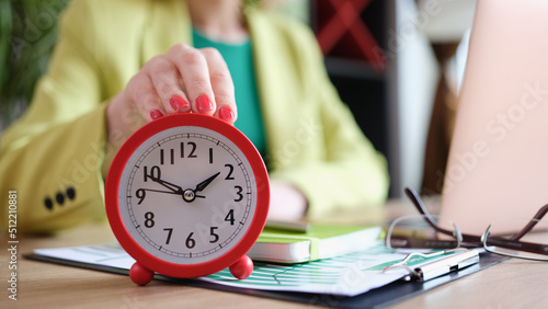 Businesswoman putting alarm clock on table, time management and deadline