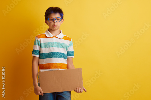 a boy with glasses on a yellow background with different emotions, holds a cardboard banner with empty space for text