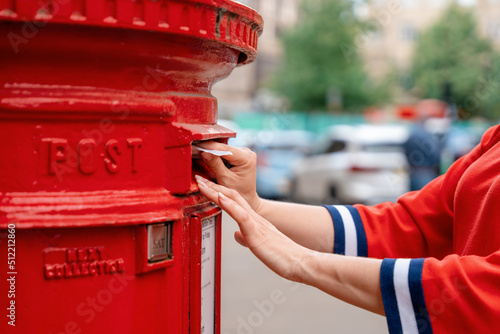 Murais de parede woman in red short posting letters in red post box in England