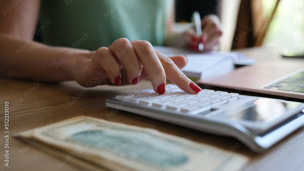 Woman doing calculation of expenses and income and making notes Woman doing calculation of expenses and income and making notes