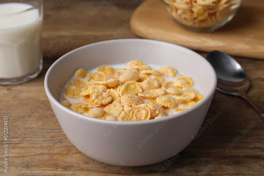 Tasty cornflakes with milk in bowl on wooden table Tasty cornflakes with milk in bowl on wooden table