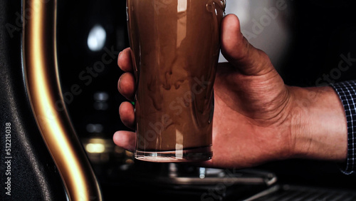 Tableau sur toile Barman in plaid shirt pouring a pint of cold dark beer into a clear glass