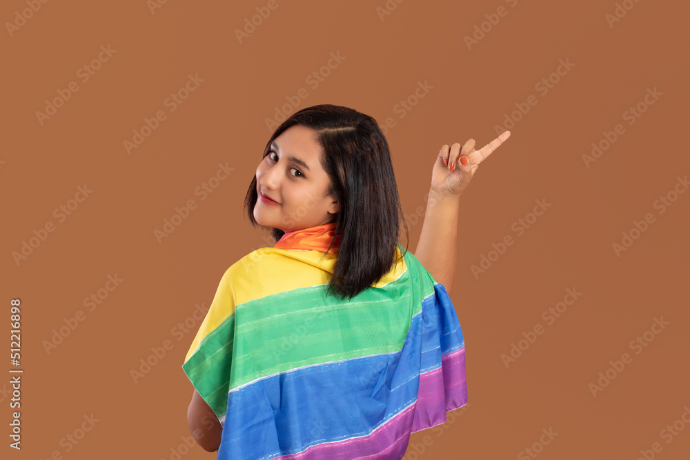 young Mexican brunette woman smiling and pointing with plain brown background young Mexican brunette woman smiling and pointing with plain brown background