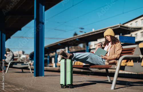 Young traveler woman sitting alone at train station platform with luggage.