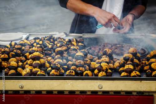 The cook roasts chestnuts in a kiosk on the street.