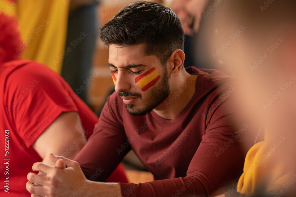 Obraz premium Worried football fans supporting spanish national team in live soccer match at stadium.
