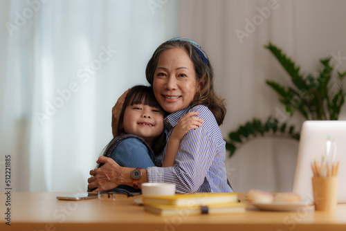Happy moments of Granddaughter give hug while Asian senior business woman working at home. Family concept.