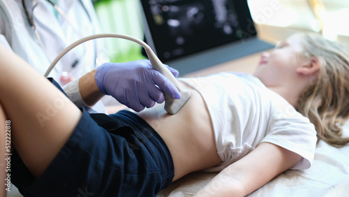 Practitioner examines with ultrasound of internal organs of little girl in clinic