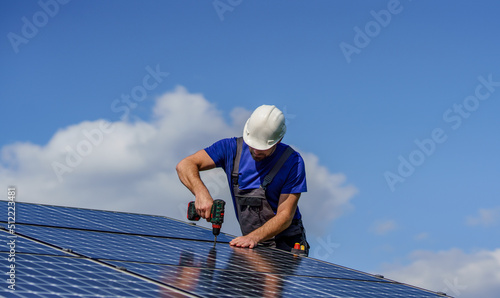 Foto Man worker installing solar photovoltaic panels on roof, alternative energy concept