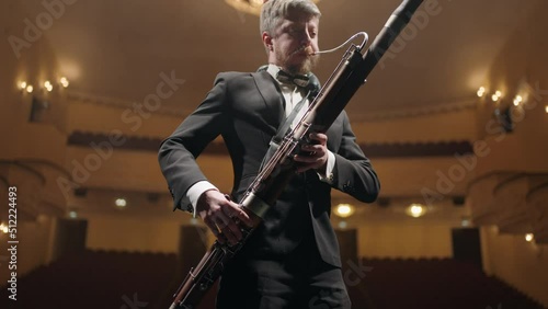 rehearsing in opera house or philharmonic hall, bassoonist is playing music on scene, portrait photo