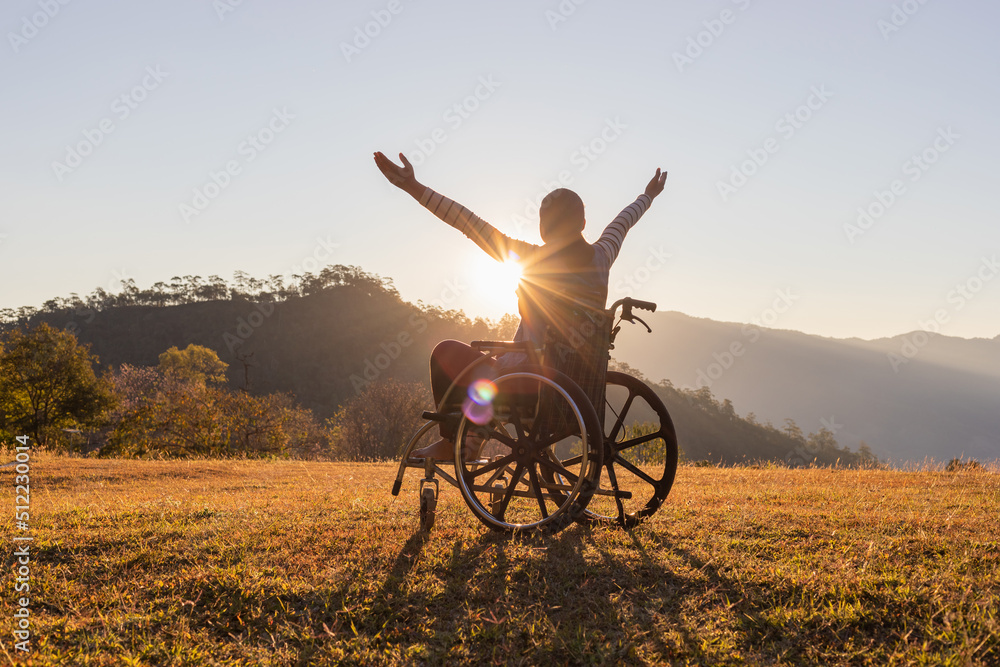 Woman sitting on a wheelchair enjoying sundown on mountain background. Woman sitting on a wheelchair enjoying sundown on mountain background.