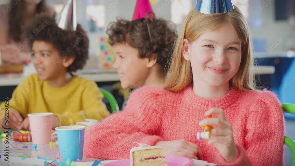 Portrait of girl sitting at table with party blower celebrating birthday and eating piece of birthday cake - shot in slow motion Portrait of girl sitting at table with party blower celebrating birthday and eating piece of birthday cake - shot in slow motion