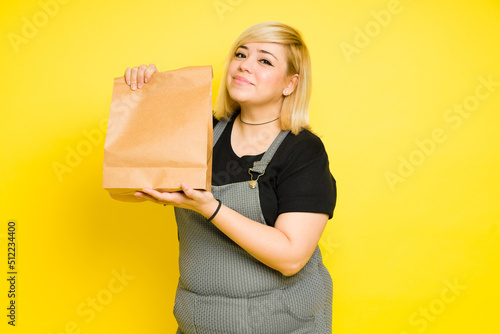 Pretty fat woman getting food delivered while holding a takeout bag in a studio photo