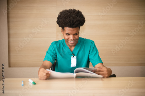 American medical student is reading a book to prepare for an exam in a hospital.