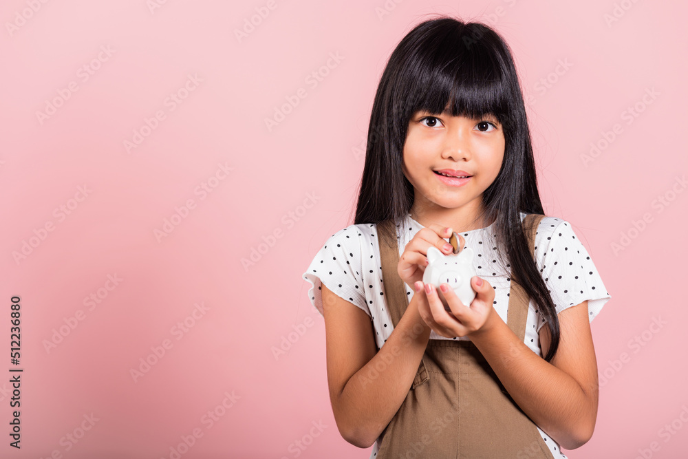 Asian little kid 10 years old holding piggy bank and looking at camera at studio shot isolated on pink background, Happy child girl lifestyle smiling with is full piggybank, Personal money savings Asian little kid 10 years old holding piggy bank and looking at camera at studio shot isolated on pink background, Happy child girl lifestyle smiling with is full piggybank, Personal money savings