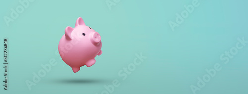 Pink piggy bank floating on blue background - savings concept photo