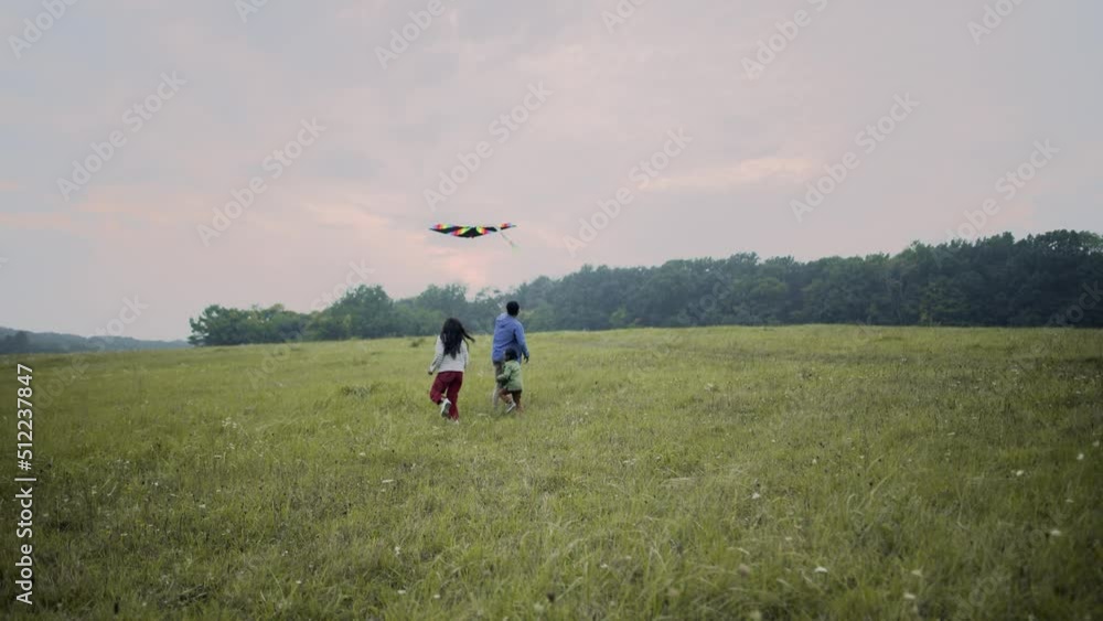 Happy African American family with child running in field flying a kite into the sky. Young joyful positive parents playing with little kid in nature spending time together, childhood concept Happy African American family with child running in field flying a kite into the sky. Young joyful positive parents playing with little kid in nature spending time together, childhood concept