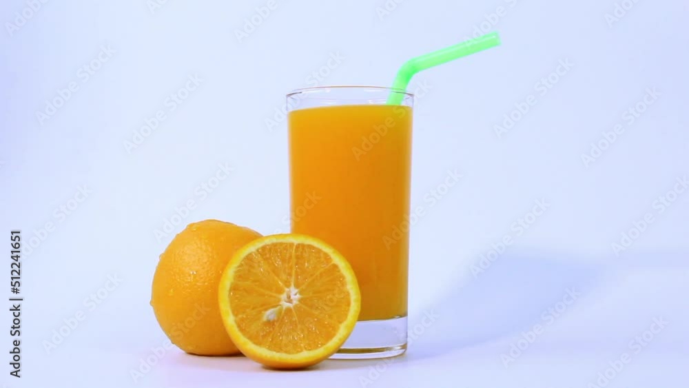 Glass of orange juice with orange sliced in half isolated on white background with green pipe Glass of orange juice with orange sliced in half isolated on white background with green pipe