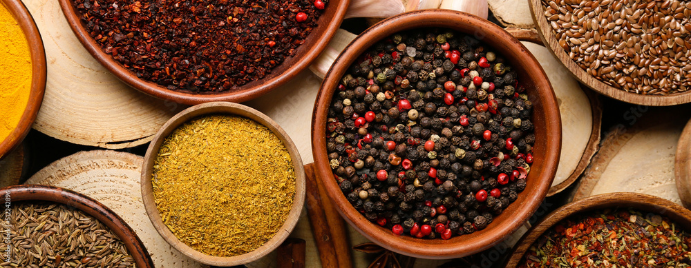 Bowls of different spices on wooden background, top view