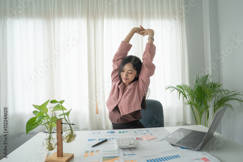 Businesses or working lady is stretch themselves or lazily for relaxing on their desk while doing their work in the office.