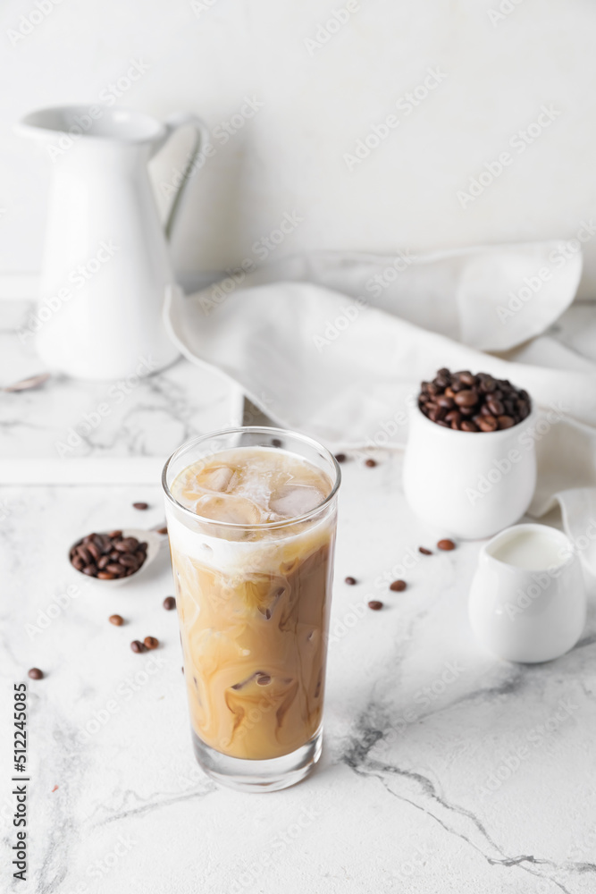 Glass of cold brew with milk and coffee beans on white marble table Glass of cold brew with milk and coffee beans on white marble table