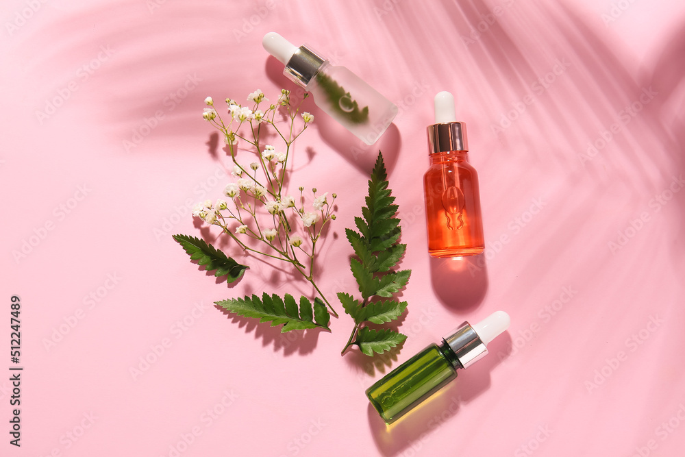 Bottles of natural serum, fern leaves and gypsophila flowers on pink background Bottles of natural serum, fern leaves and gypsophila flowers on pink background