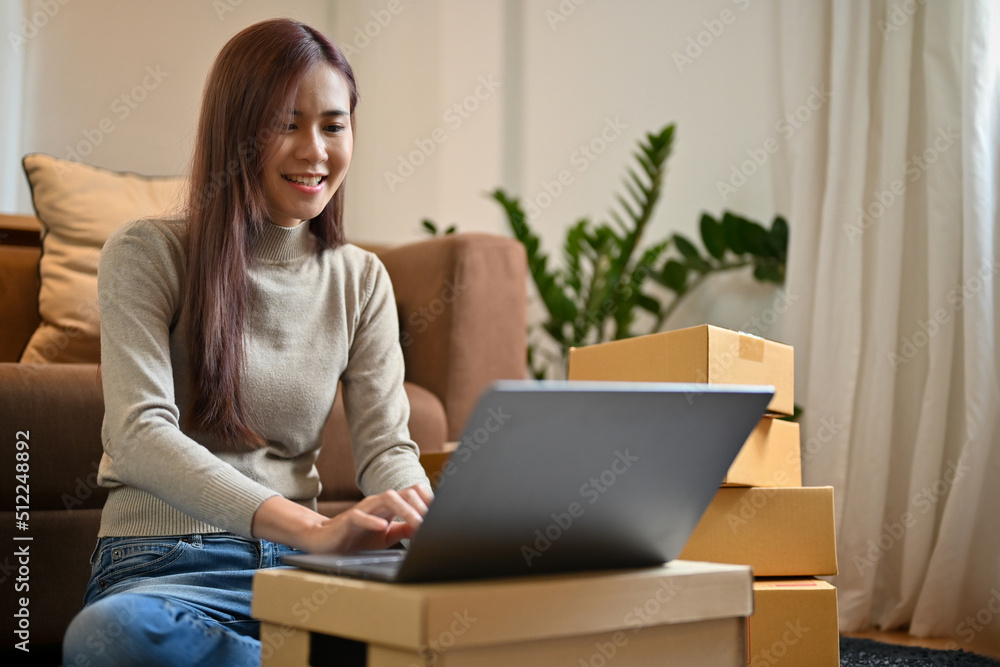 Asian female e-commerce business entrepreneur updating her stock on the website Asian female e-commerce business entrepreneur updating her stock on the website