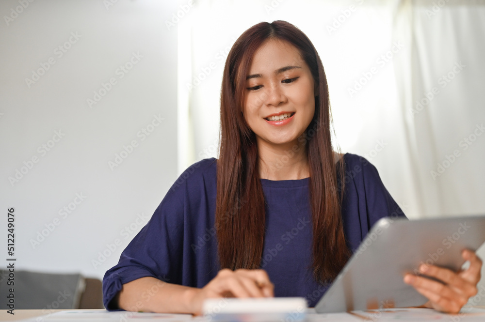 Beautiful Asian woman using calculator, calculating her monthly expenses and income. Beautiful Asian woman using calculator, calculating her monthly expenses and income.