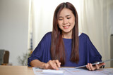Asian businesswoman calculating her business income and profit on the financial report.