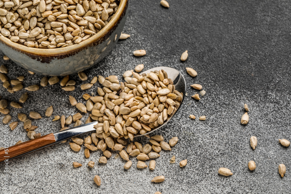 Bowl of peeled sunflower seeds with spoon on black and white background, closeup Bowl of peeled sunflower seeds with spoon on black and white background, closeup